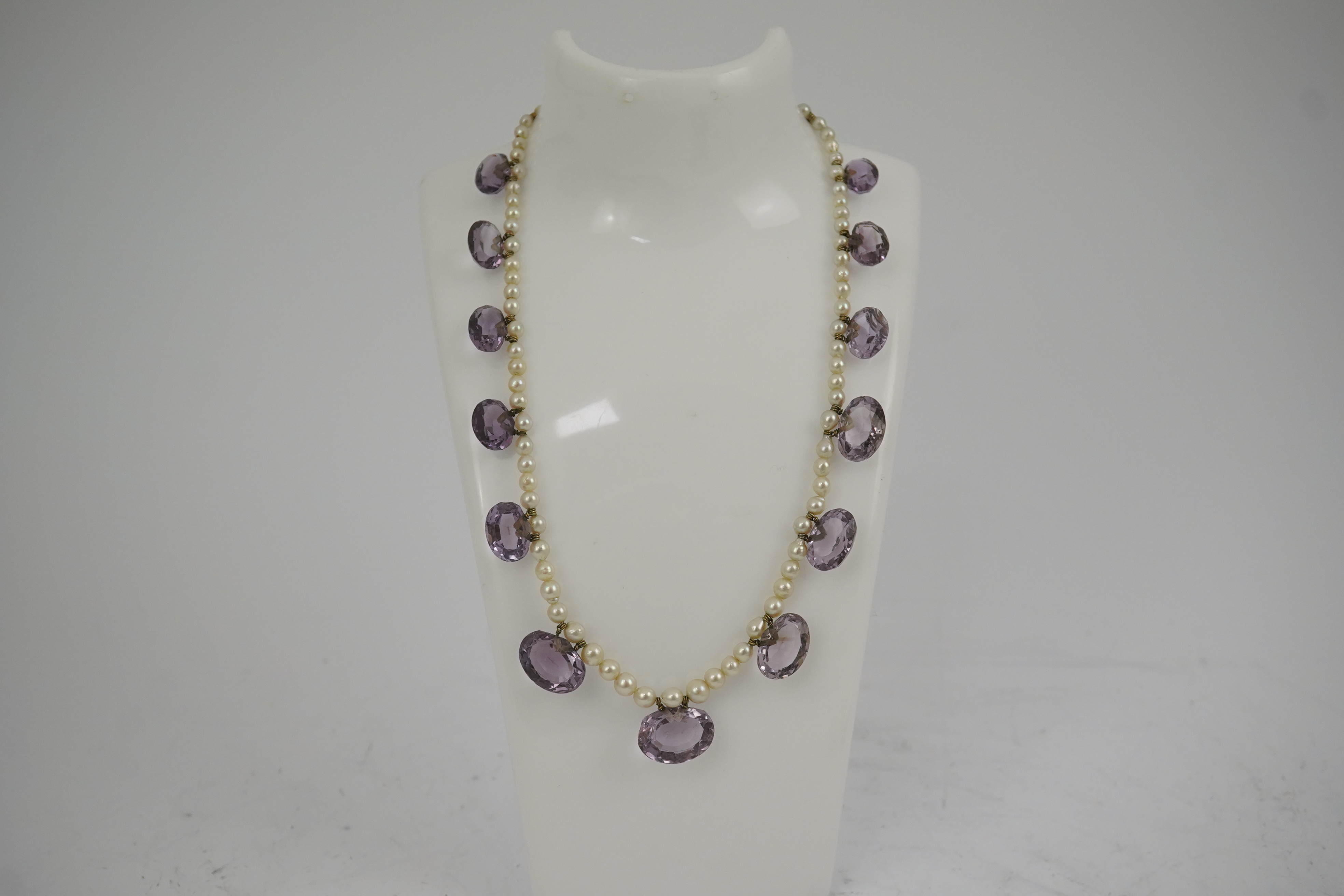 A 19th century pearl and graduated fifteen stone oval cut amethyst set drop necklace, with a gold barrel shaped clasp